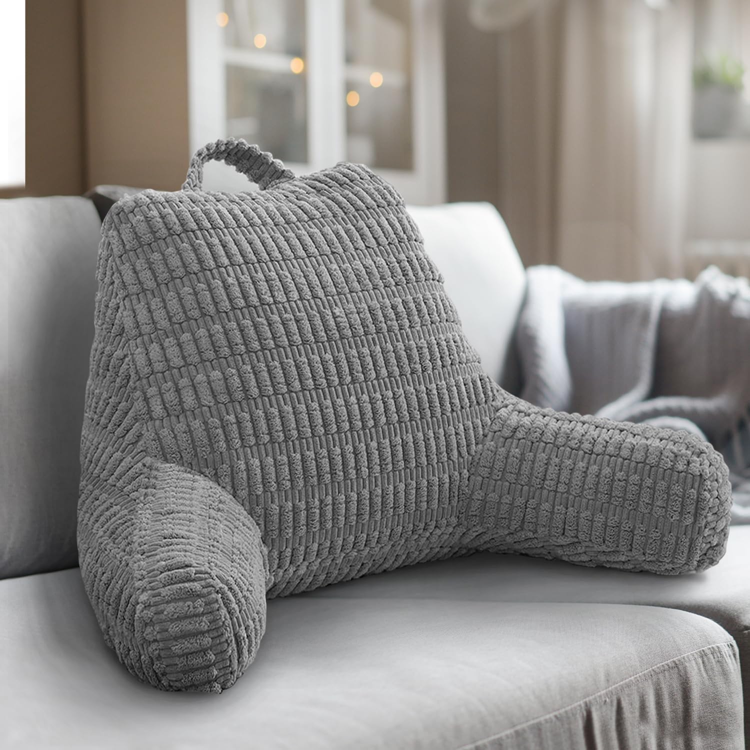 Gray textured backrest pillow on a sofa in a cozy living room.