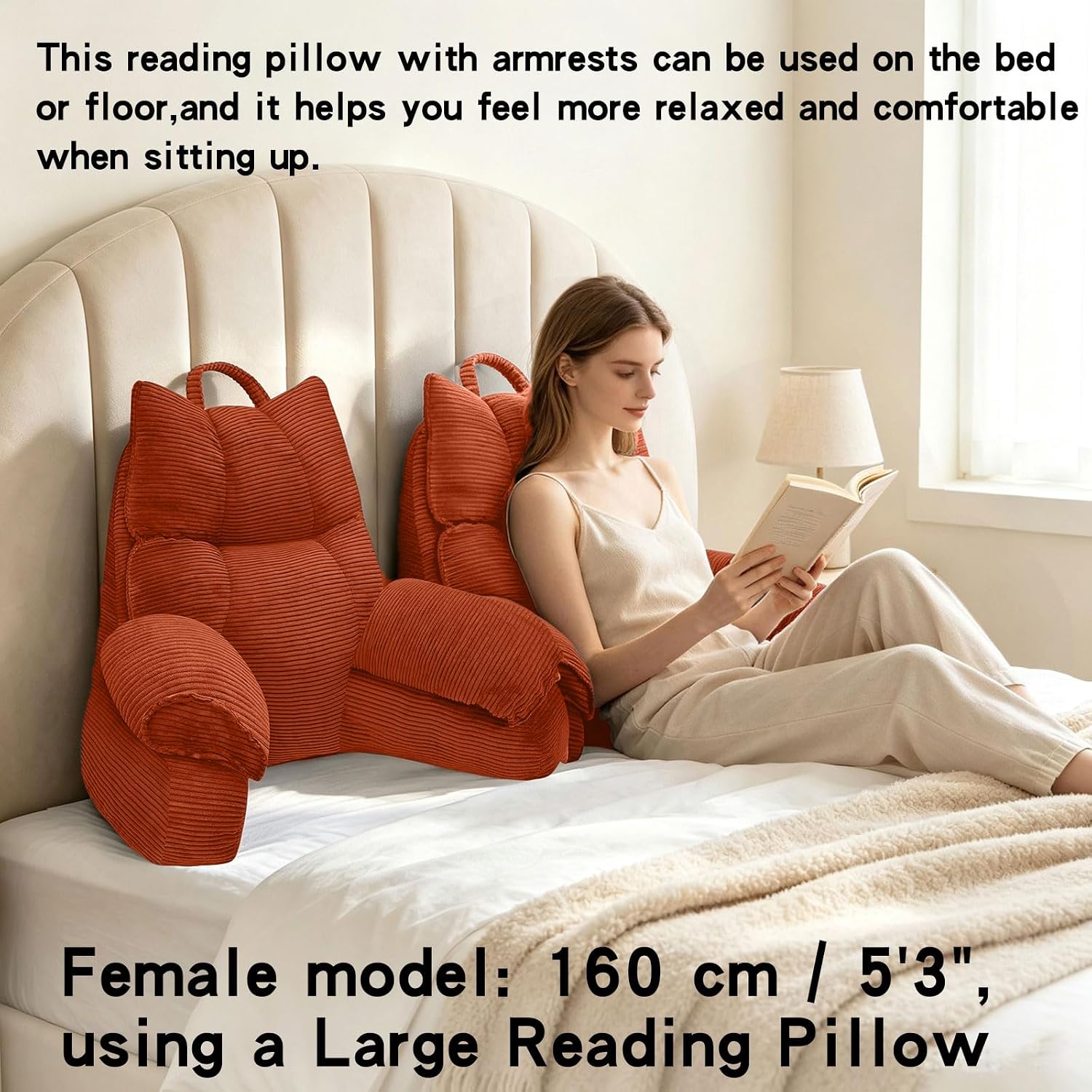 A woman sits on a bed reading a book, supported by two rust-orange ribbed reading pillows with armrests. The scene is a softly lit bedroom with a cream upholstered headboard, white bedding, and text describing the product and its use.